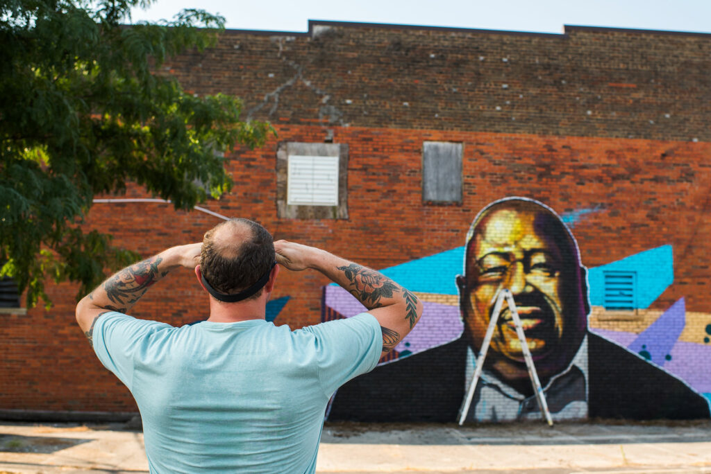 man looking at mural on brick wall