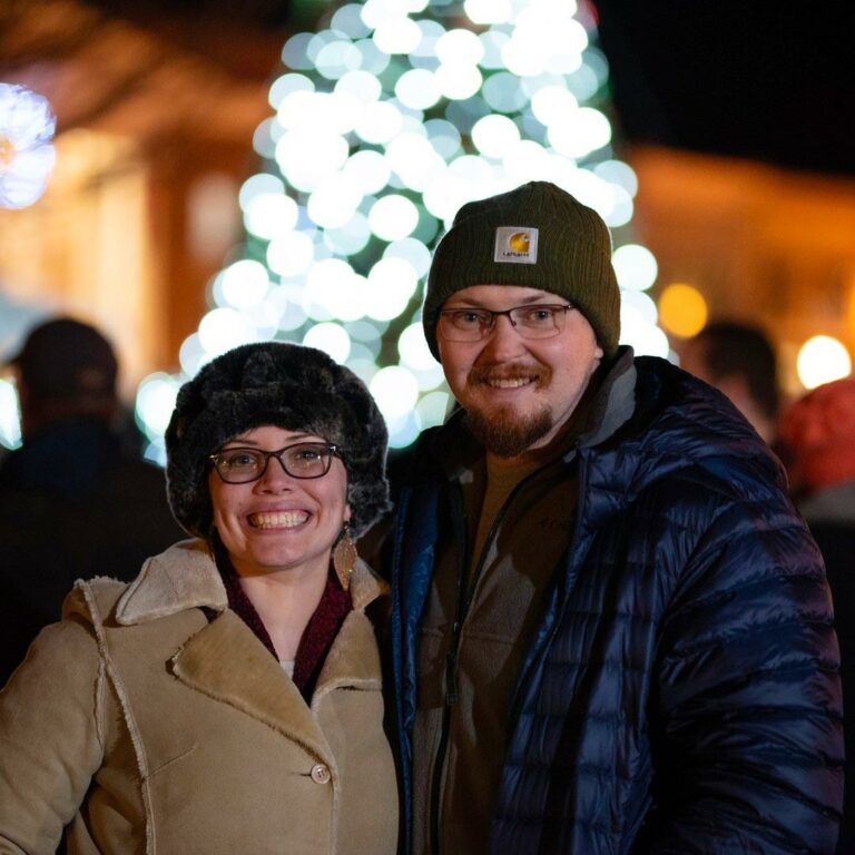 Couple in winter clothes outside in downtown Somerset at night.