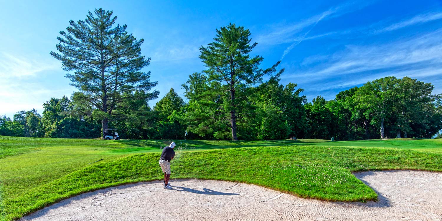 man with golf club in sand trap