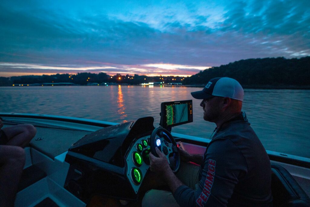 man driving a fast fishing boat at sunset on the lake