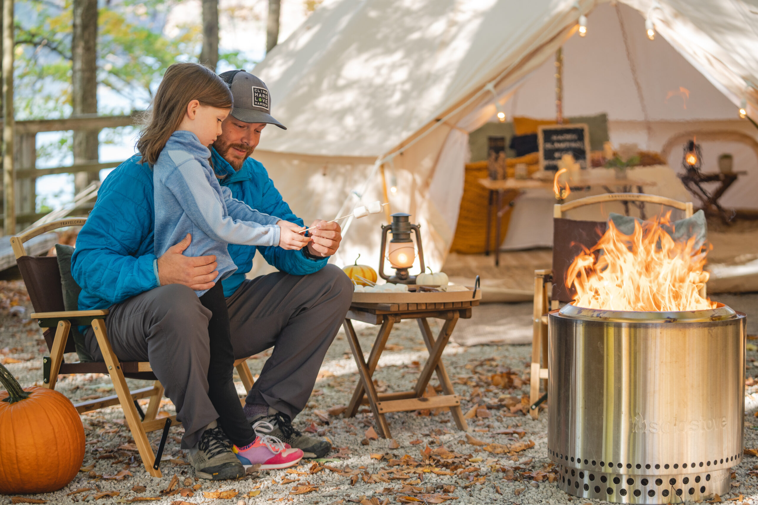 father and daughter roasting marshmallows while glamping