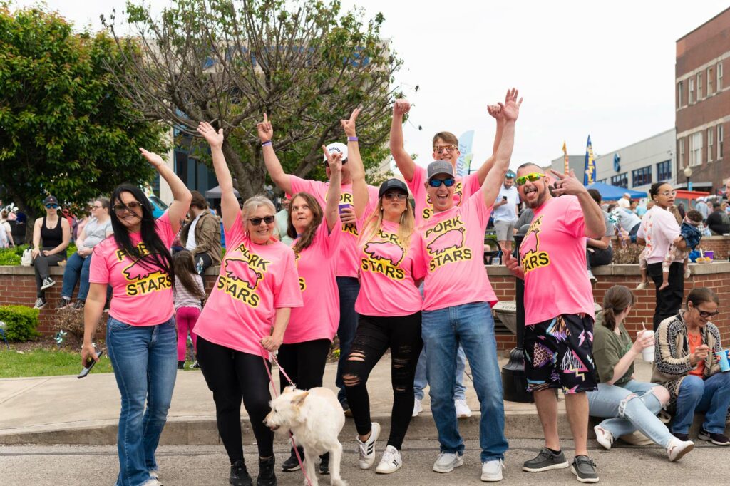 Excited people with their arms in the air and matching tshirts that say "PORK STARS"