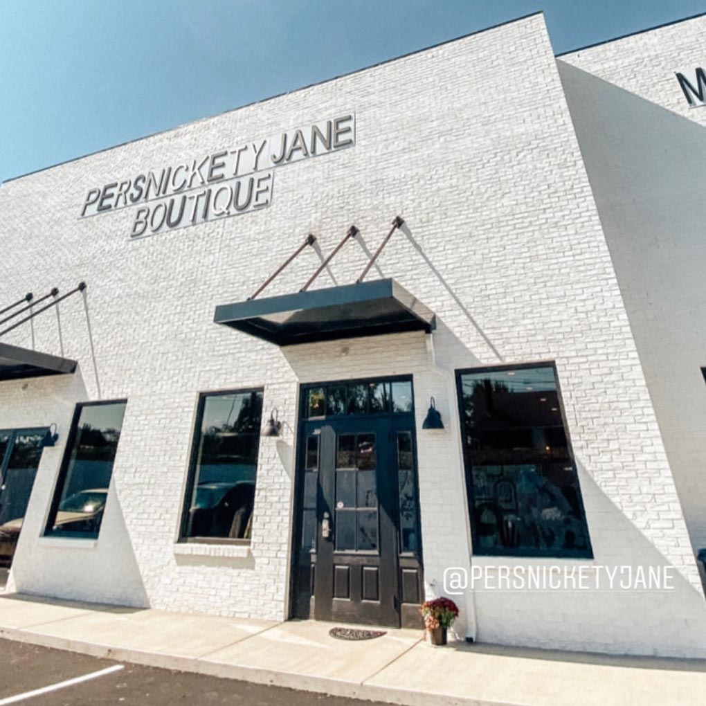 white brick store exterior with persnickety jane sign above entrance