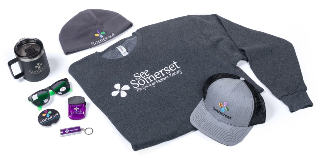 group of City of Somerset branded promotional items including a sweat shirt, knit cap, ball cap, mug, sunglasses, keychain, badge, and clip