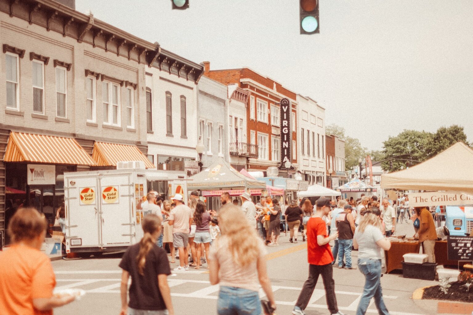 People walking through downtown streets visiting vendors in food trucks and tents.